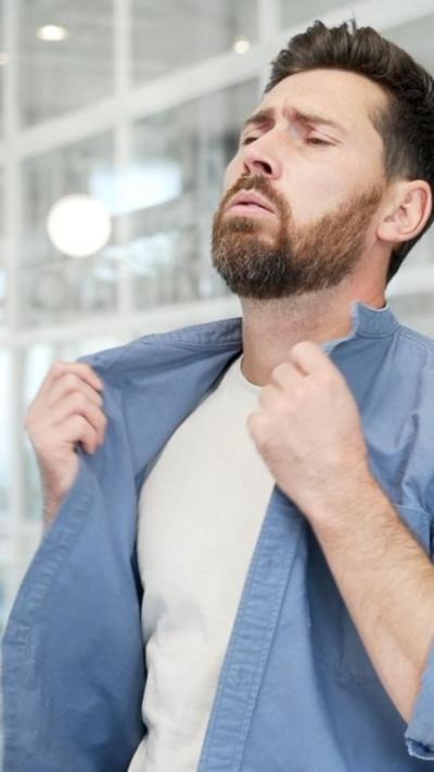 A man holds open his shirt, he looks warm