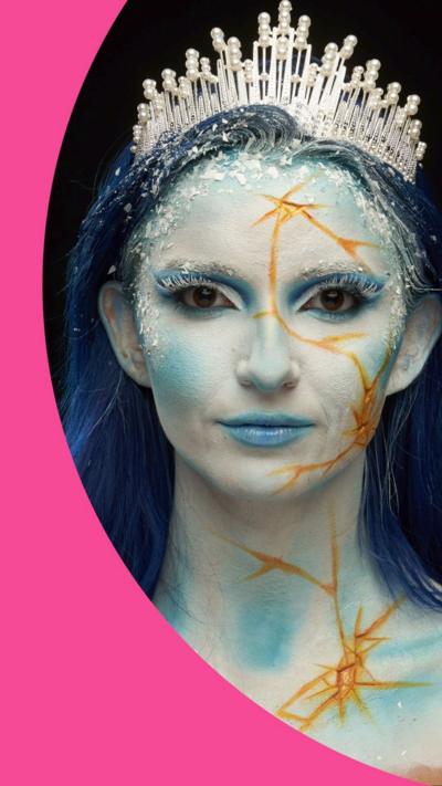 Mia has dark blue hair. She is wearing a tiara and has a white and blue, frozen like, makeup look.