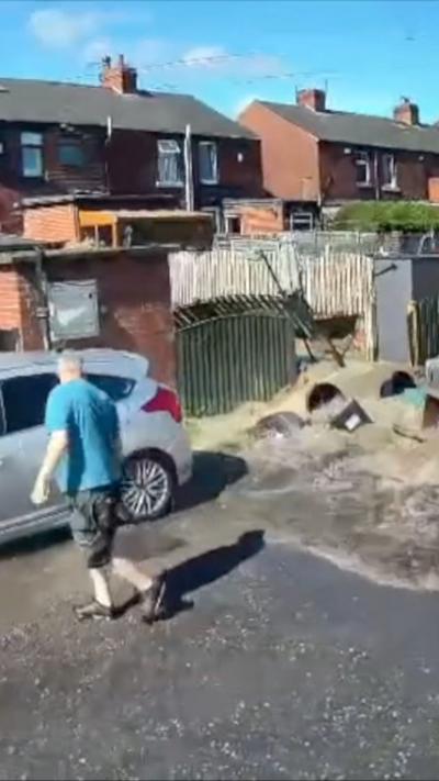 CCTV footage of a number of gardens and parking spaces flooded with brown water.