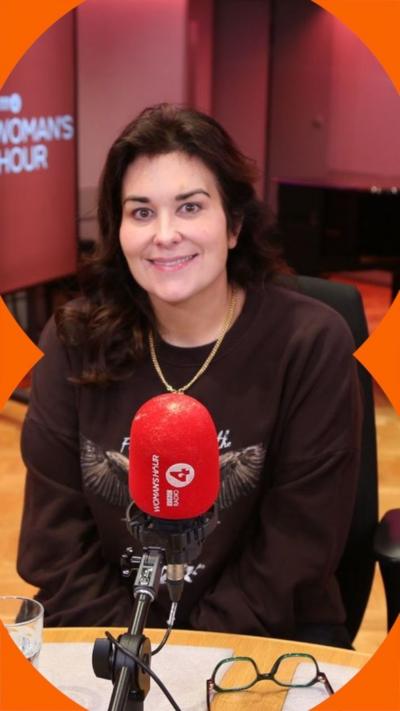 Woman with long dark hair, wearing a brown sweatshirt and a gold necklace.