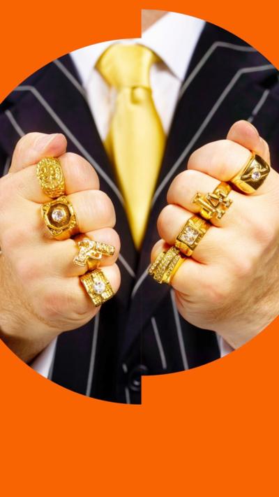 Close up of a person's hands wearing one big gold ring per finger