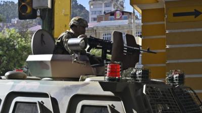 Soldier on top of an armoured vehicle, holding a gun