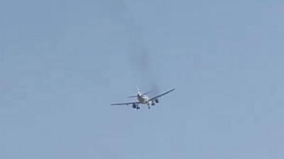 A plane is seen with smoke coming from its engine.