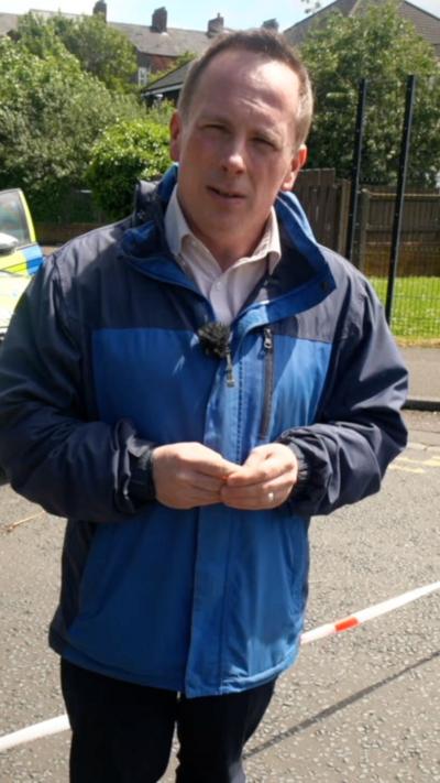 Chris Page in a blue jacket with his hands clasped.