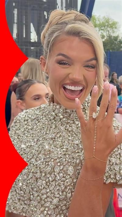 Molly Smith smiling and holding up her hand to show her engagement ring