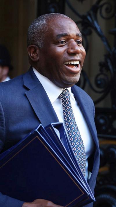 David Lammy smiling wearing a blue suit, side view.