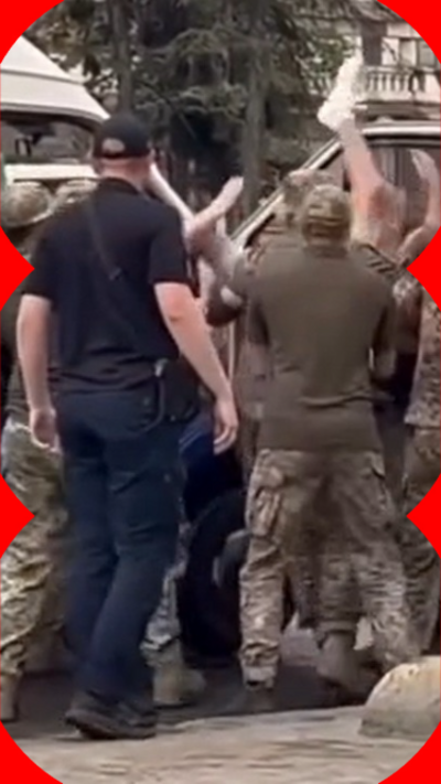 A group of men in military uniforms drag another man into a van
