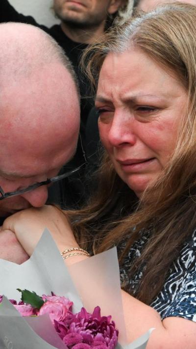 Close-up of man kissing woman's hand who is crying. 