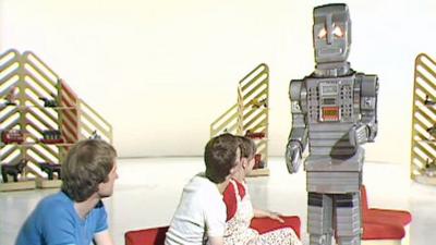 Marvin the Paranoid Android stands beside three Blue Peter presenters