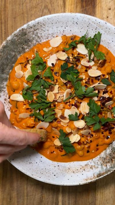 An orange-coloured chickpea based dish on a white plate