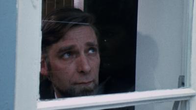 Homeowner peering out through window