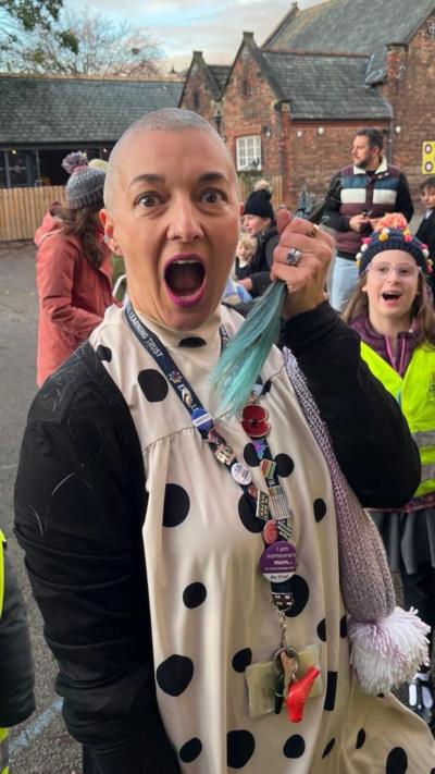 Laura Taylor, a teaching assistant with a shaved head holding a lock of her hair