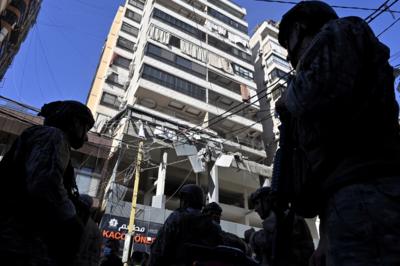 Members of Hezbollah and the Lebanese army stand outside a building hit by an Israeli air strike