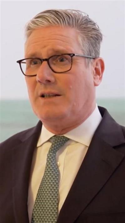 UK PM Keir Starmer wearing glasses, white shirt, green tie and dark blazer