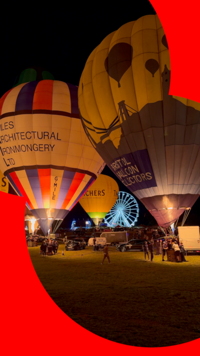 A number of hot air balloons in Bristol on the opening night of the festival. Two balloons stand out against the night sky with a Ferris wheel visible off in the distance