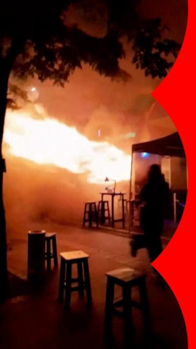 A person runs as fire spills out of the entrance to a bar