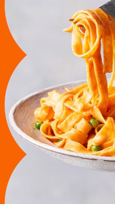 A bowl of creamy tagliatelle with a fork holding up a spoonful.