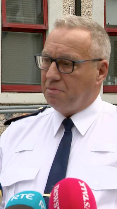 Supt Watters has short grey hair and is wearing dark square glasses with his uniform which is a white shirt and black tie.