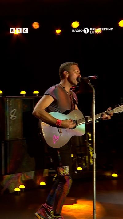 Coldplay at Radio 1 Big Weekend festival. The stage is lit up with colour.
