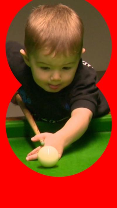 A boy toddler playing snooker
