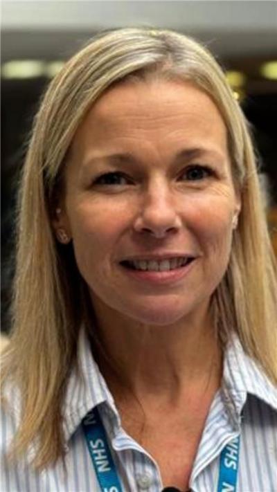 Close up of blonde woman smiling wearing an NHS lanyard