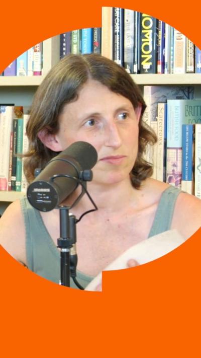 A woman with brown hair speaks into a microphone.