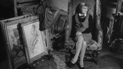 Poet and novelist Stevie Smith sitting in her home next to framed pictures.