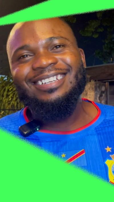 Football fan in blue and red Congolese football kit smiling to the camera