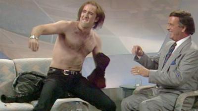 Nicholas Cage taking off his T-shirt next to Terry Wogan.