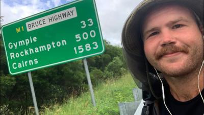 Man standing in front of a road sign