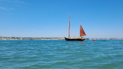A small boat on a calm, turquoise sea with blue skies overhead.