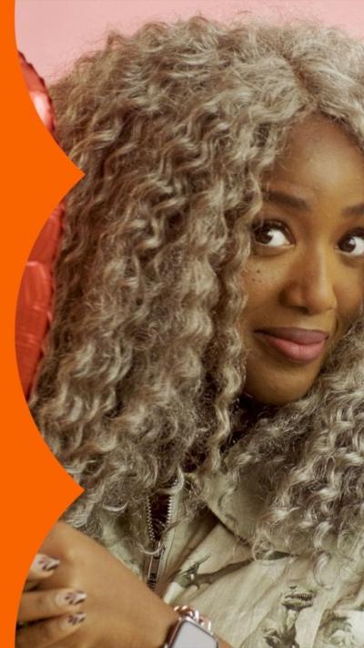 Woman with long curly hair holding heart-shaped balloon
