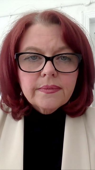 Paula Barker, wearing glasses and polo neck 