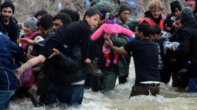 Migrants crossing a river near the Macedonian border