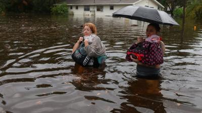 Two women evacuate their home after flood waters from Hurricane Idalia inundated it in Tarpon Springs, Florida