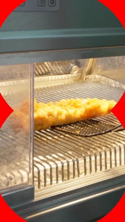 A piece of battered fish in a heated cabinet
