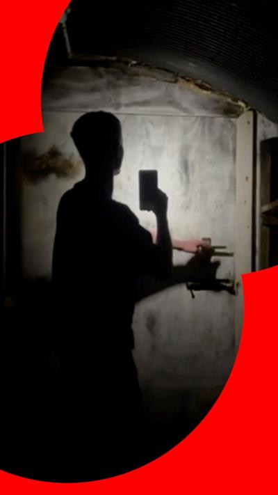 A silhouette of a man holding a phone in a dark tunnel