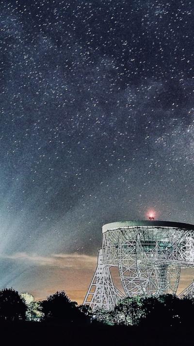 The Lovell telescope shining on a dark clear night at Jodrell Bank 