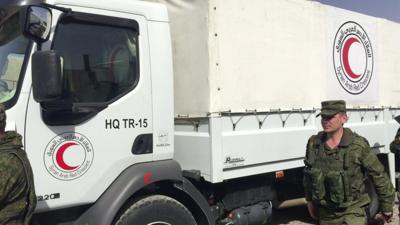 A Syrian Red Crescent truck waits to move forward with Russian soldiers keeping guard