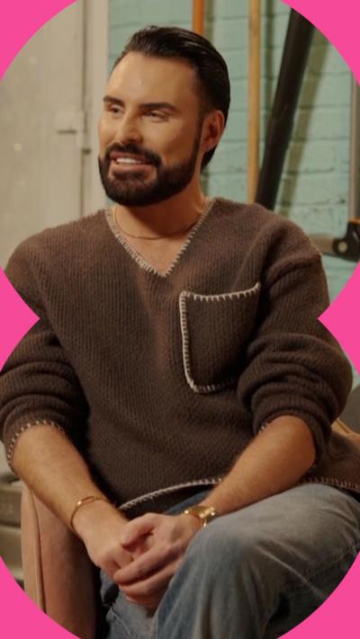 Martin Clunes and Romesh Ranganathan shake hands whilst sat down on an orange sofa.