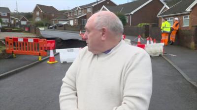 Man looks back at a wall falling into a sinkhole