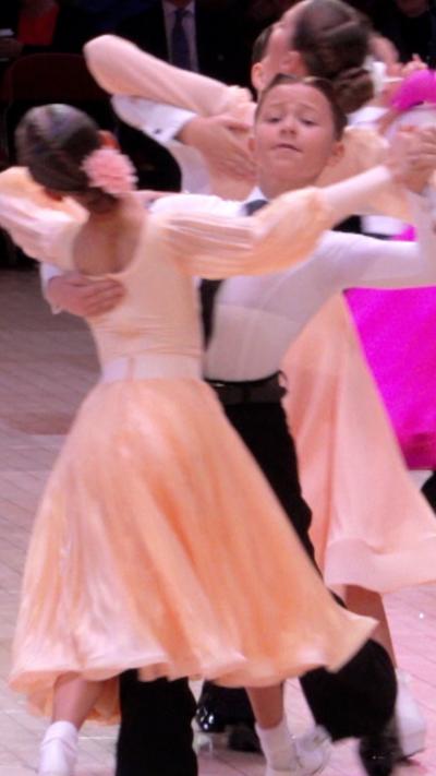 A young boy and a young girl in ballroom clothing are in a ballroom hold.