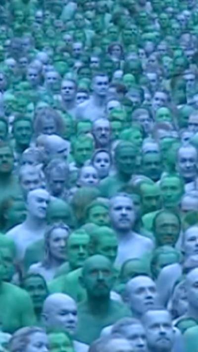 A sea of blue faces are stood in a crowd. There are two different shades of blue.