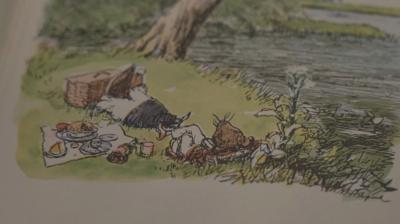 Illustration from Wind in the Willows book shows Mole by the banks of a river relaxing with a picnic beside him.