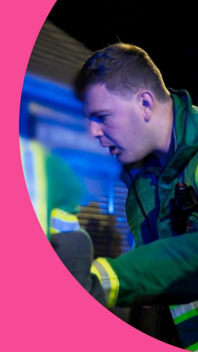A paramedic looks down at the ground with a stunned look on his face