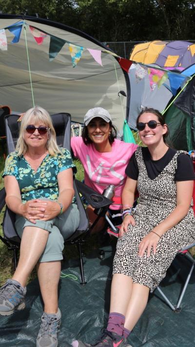 Anita Rani with a mother and daughter outside a tent