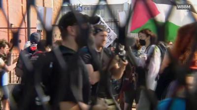 A group of people are seen through fencing with one carrying a Palesstinian flag