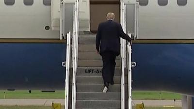 Trump boarding a plane with paper stuck to his shoe