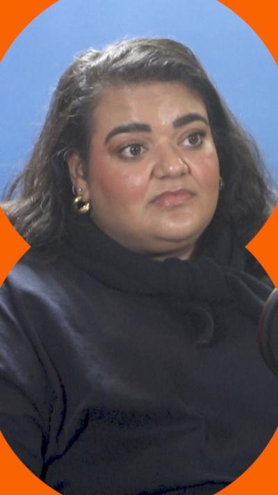 Billie Bhatia has long dark hair and is wearing a dark top.