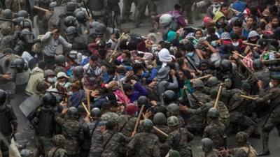 Thousands of US-bound migrants are met by security guards at the Guatamala border with Honduras.